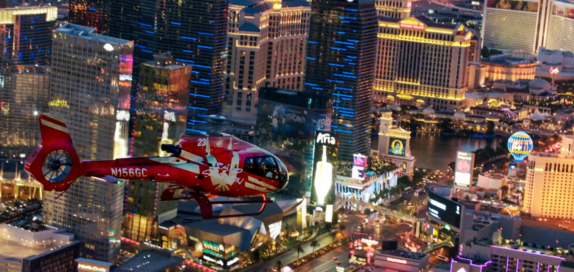 Red helicopter flying over Las Vegas Strip EcoStar Helicopter flying over the Las Vegas at night with views of iconic Las Vegas Strip in the background