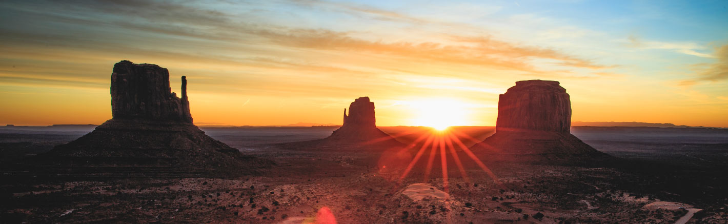 The sun rises over Monument Valley.