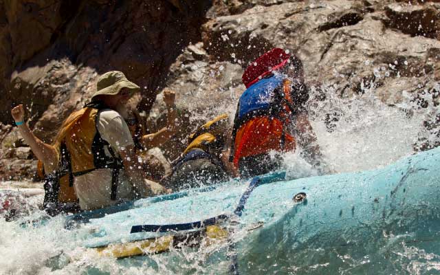 Water splashes on passengers aboard a raft.