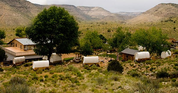 The Bar 10 Ranch property set amidst canyon scenery, with covered wagons scattered in the foreground.'